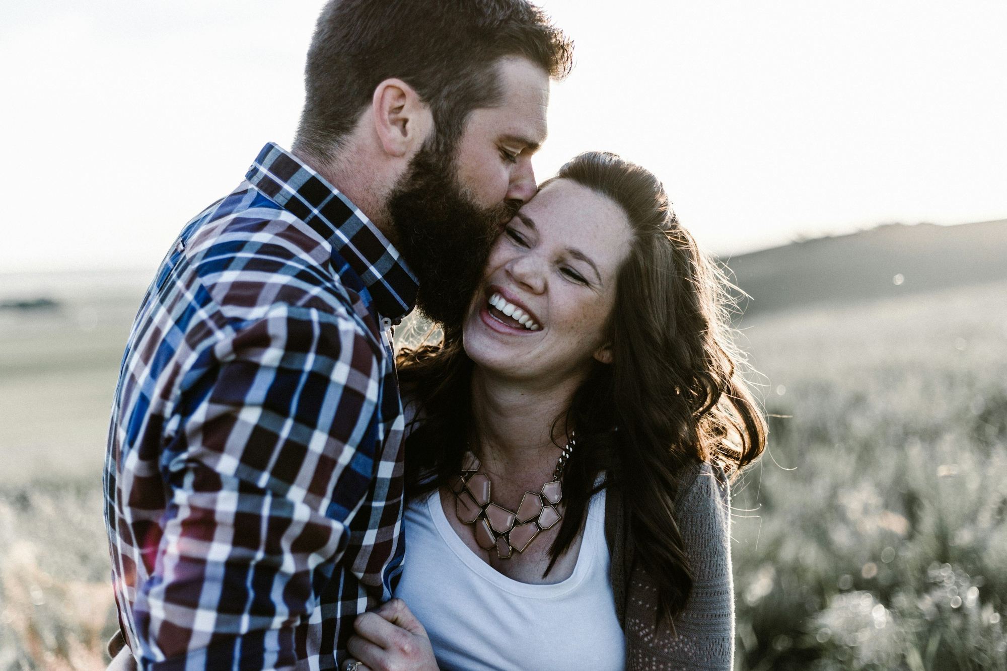 A laughing couple embracing outdoors in soft daylight